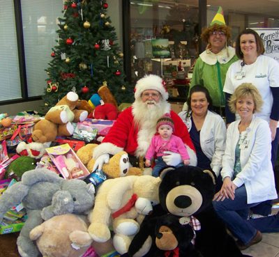 Conway Regional’s Jo Lynne Gasaway, Theresa Tidwell, Jeanie Hernandez and Macee Raye Tidwell join Santa and Buddy the Elf with toys collected by area bikers for pediatric patients at the hospital.