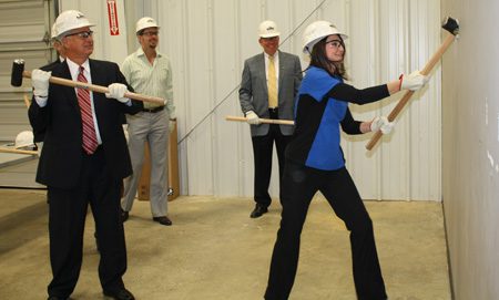 Kristen Riddle (right) delivers the first hit during the “Knock Out the Wall Kickoff” while Eddie Glover (left) awaits his turn.