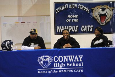 With his dad, Bryan Wilson (left), and his mom, Latisha Wilson, by his side, Conway High School senior Corven Alexander signs a national letter of intent to play football for Harding University.