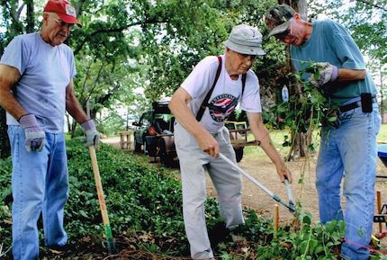 Mike Hargis (from left), A. J. Hambuchen and Deacon Larry Lipsmeyer from Hot Springs Village cut away foliage to make room for the foundations. 