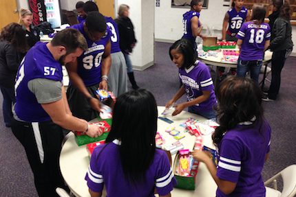 UCA football players T.J. Randall (57) and Jonathan Woodard, along with members of the UCA Football Belles, stuff shoeboxes.