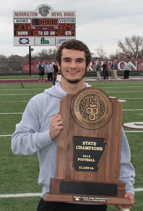 Morrilton High School senior receiver Reese Heidenreich — a 2013 501 Football Team honoree — with the state championship trophy following a community-wide assembly at Devil Dog Stadium. The scoreboard reflects the final score in the Morrilton win over Batesville for the state championship. Reese played an integral part in Morrilton’s success all season and in the championship game. Heidenreich pulled in five receptions for 96 yards and two touchdowns. 