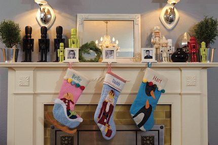 Live mini Evergreens and modern nutcrackers complement stockings waiting for Santa on the holiday fireplace mantel.