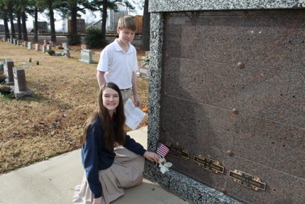 Sophomore Marley Spradlin and eighth-grader Riley Tucker place flags and flowers at SJS teacher Ray Nielsen's father's and brother's graves.